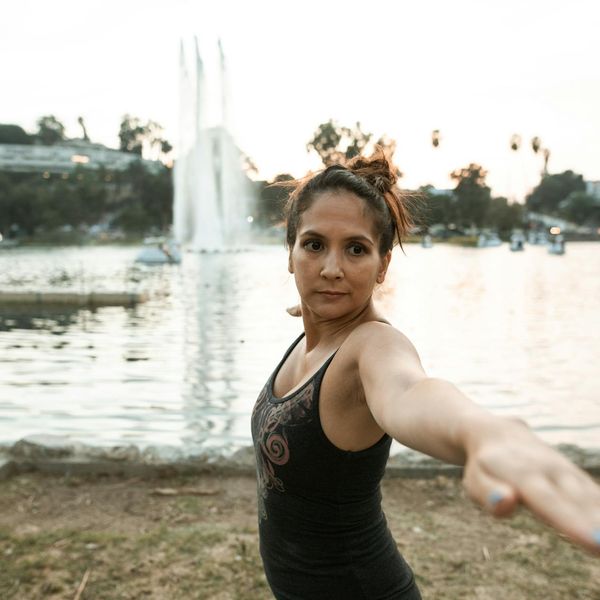 Person doing a gentle stretching yoga pose outdoors at sunset.