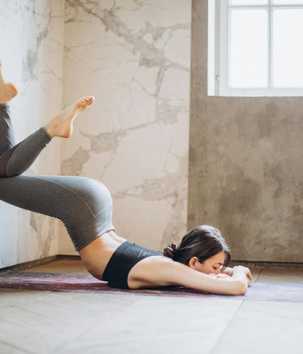 Woman in a calm yoga pose in a warmly lit room.